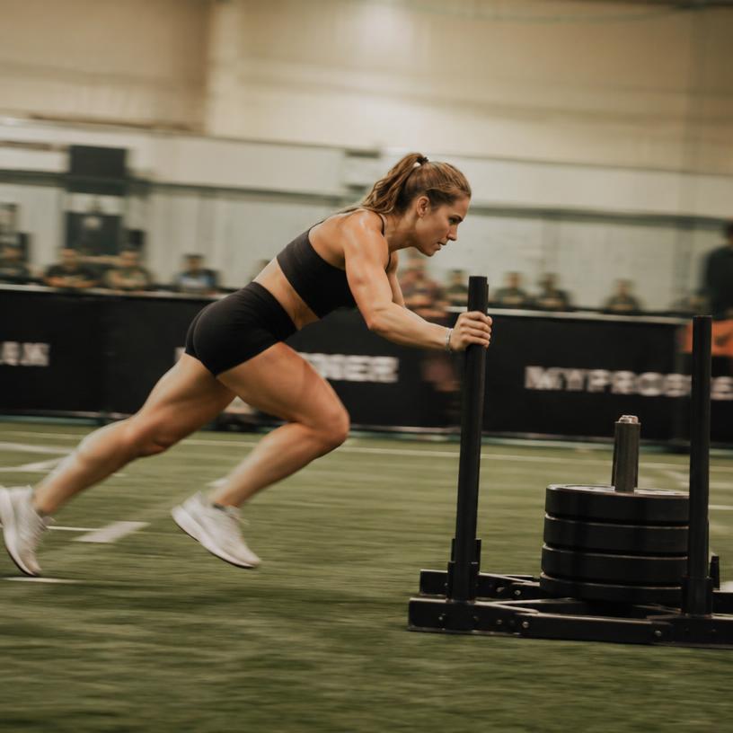 Woman pushing a weighted sled during HYROX training